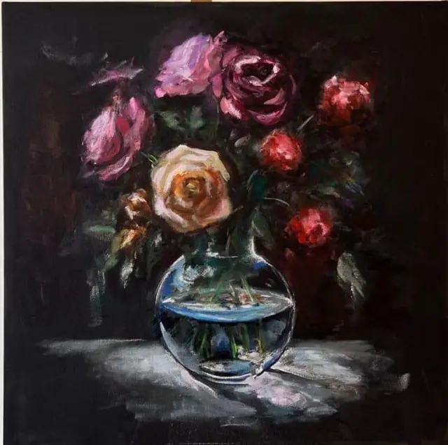 Roses in a round glass vase, on black