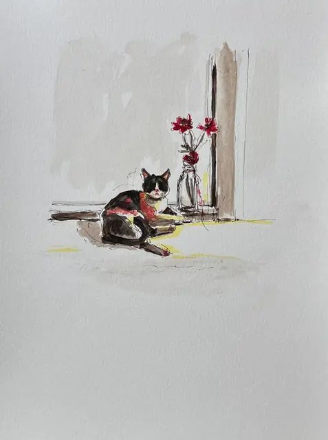 A cat beside a vase of red flowers, in a patch of sunlight