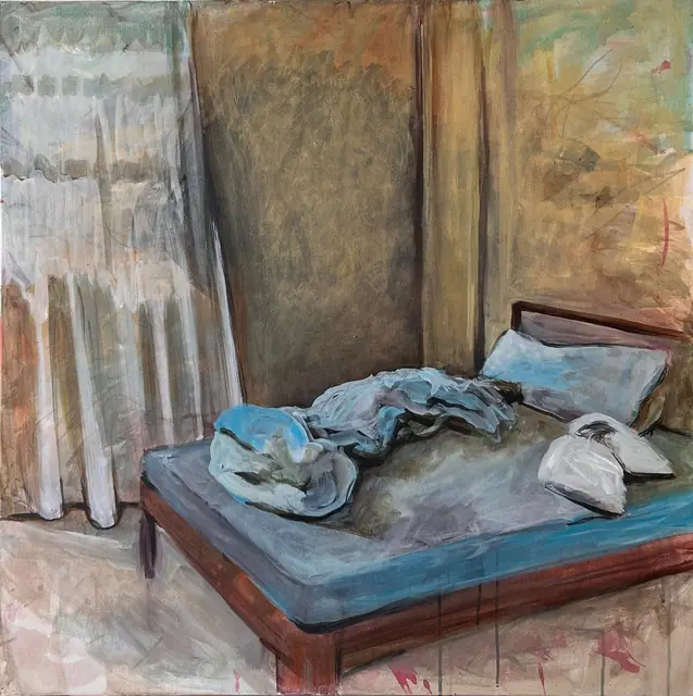 A rumpled bed with blue sheets beside white curtains