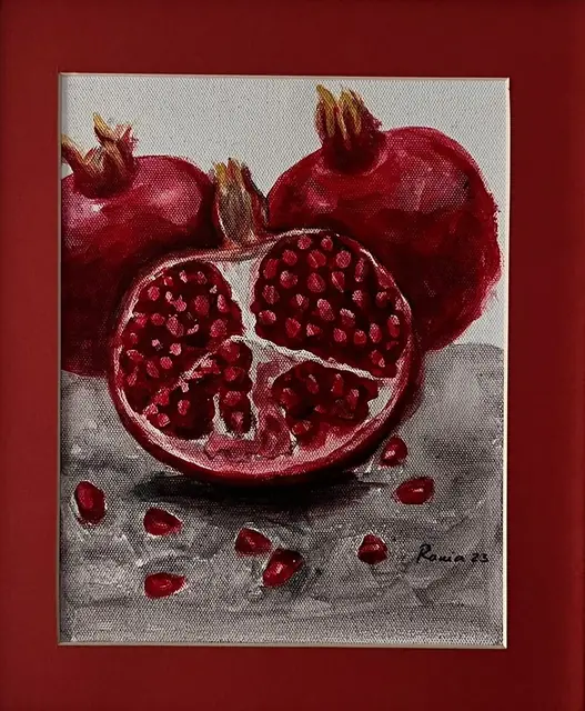 Two whole pomegranates and one cut open, on grey
