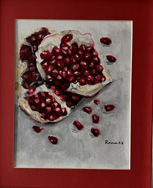 A broken pomegranate with seeds scattered on grey