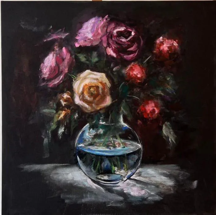 Roses in a round glass vase, on black